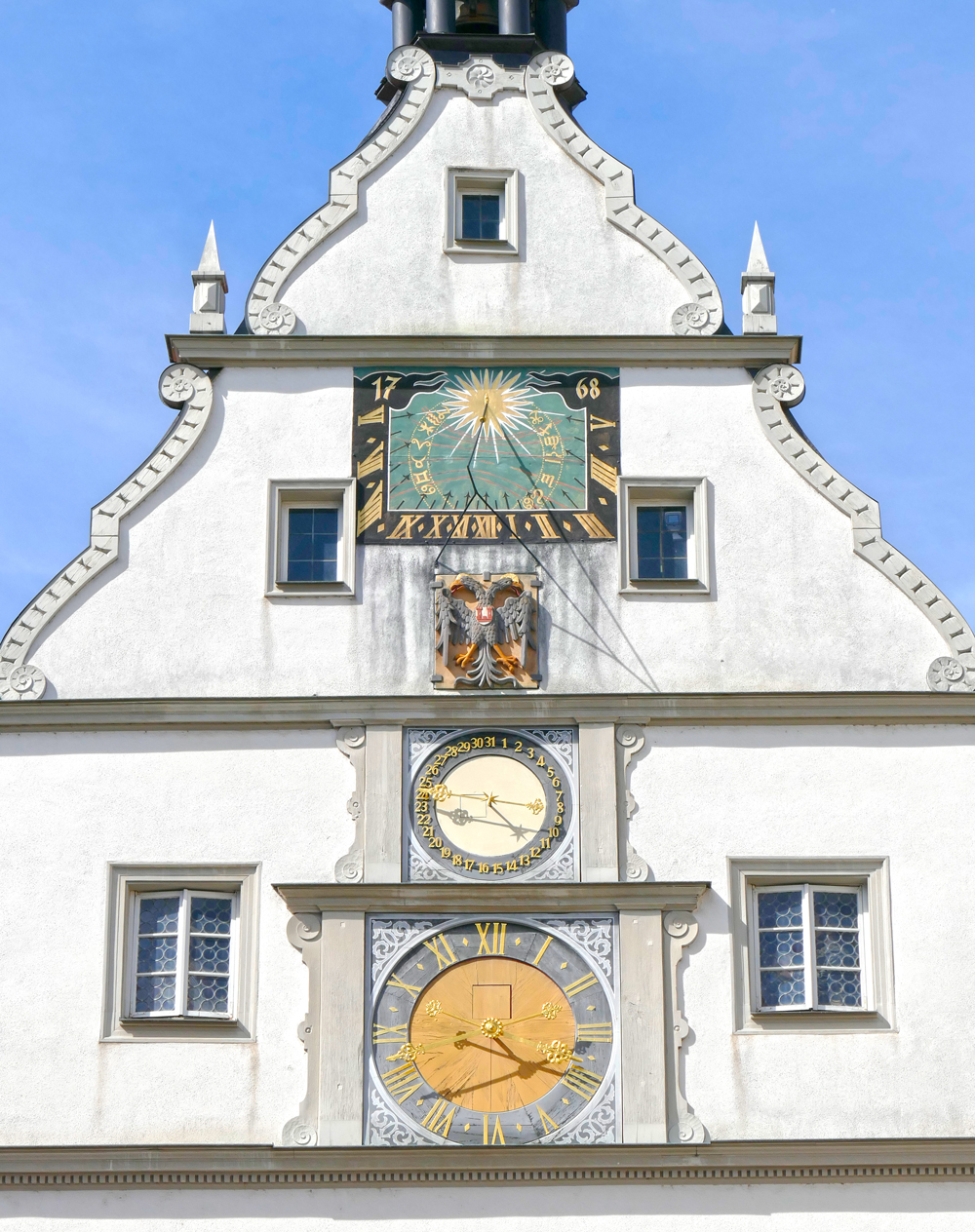 Abb. 7: Ratstrinkstube vom Marktplatz aus mit Sonnenuhr, Datums-Anzeige und Zifferblatt mit Viertelstunden- und Stundenzeiger. Die Figuren sind jeweils zur vollen Stunde in den Fenstern links und rechts der Sonnenuhr zu sehen. Foto: Silvio Marugg